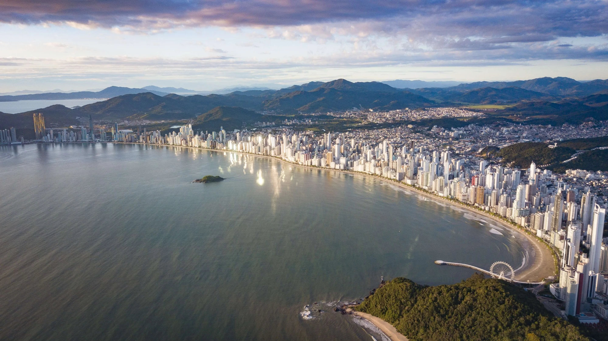 Vista aérea da praia de Balneário Camboriú, com seus impressionantes arranha-céus à beira-mar. Os altos edifícios contrastam com a extensão de areia e o azul do oceano, criando uma paisagem urbana única e moderna.